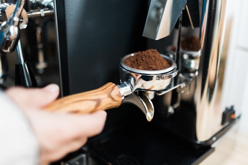 Nahaufnahme eines mit gemahlenem Kaffee gefüllten Siebträgers an einer Espressomaschine