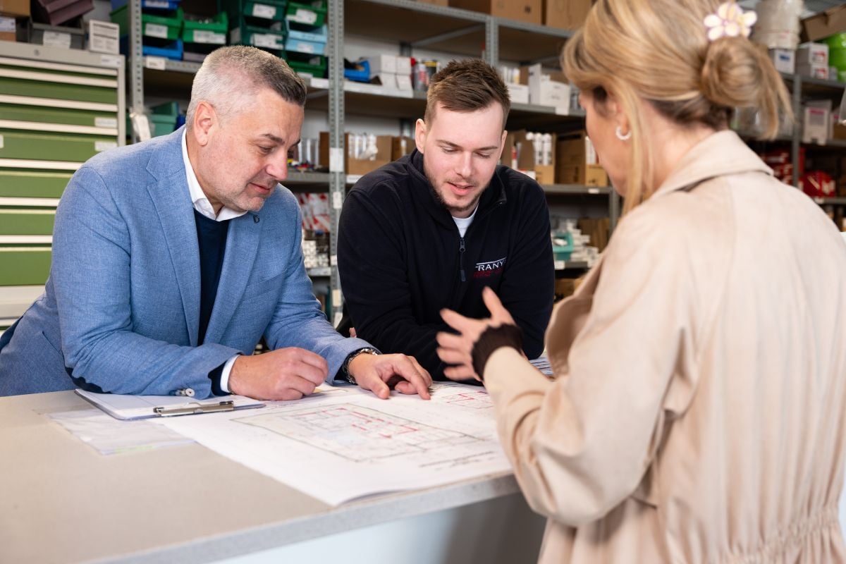 Kundengespräch zur technischen Gebäudeausstattung mit Besprechung von Plänen in einem Ersatzteillager.