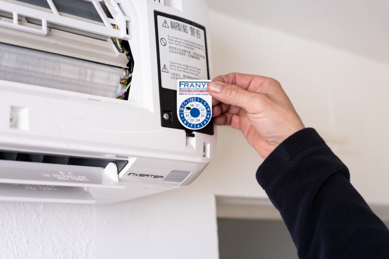 Franye Techniker führt Wartung einer Klimaanlage durch und dokumentiert den Servicezustand der Anlage