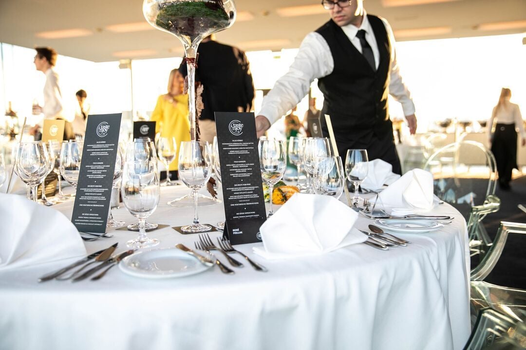 Professionell gedeckte Tische mit Menükarten und Gläsern bei einem Event von taste'njoy Premium Catering.