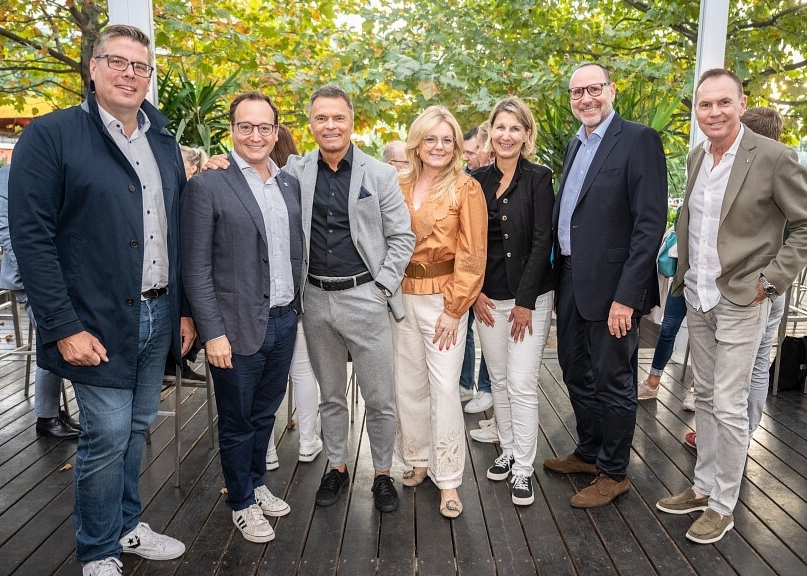 Erich Steinreiber und Partner stehen im Freien auf einer Terrasse, lächeln und blicken in die Kamera