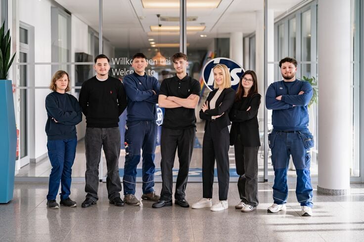 Junge Mitarbeitende in Arbeitskleidung im praktischen Einsatz in einem Ausbildungsumfeld.