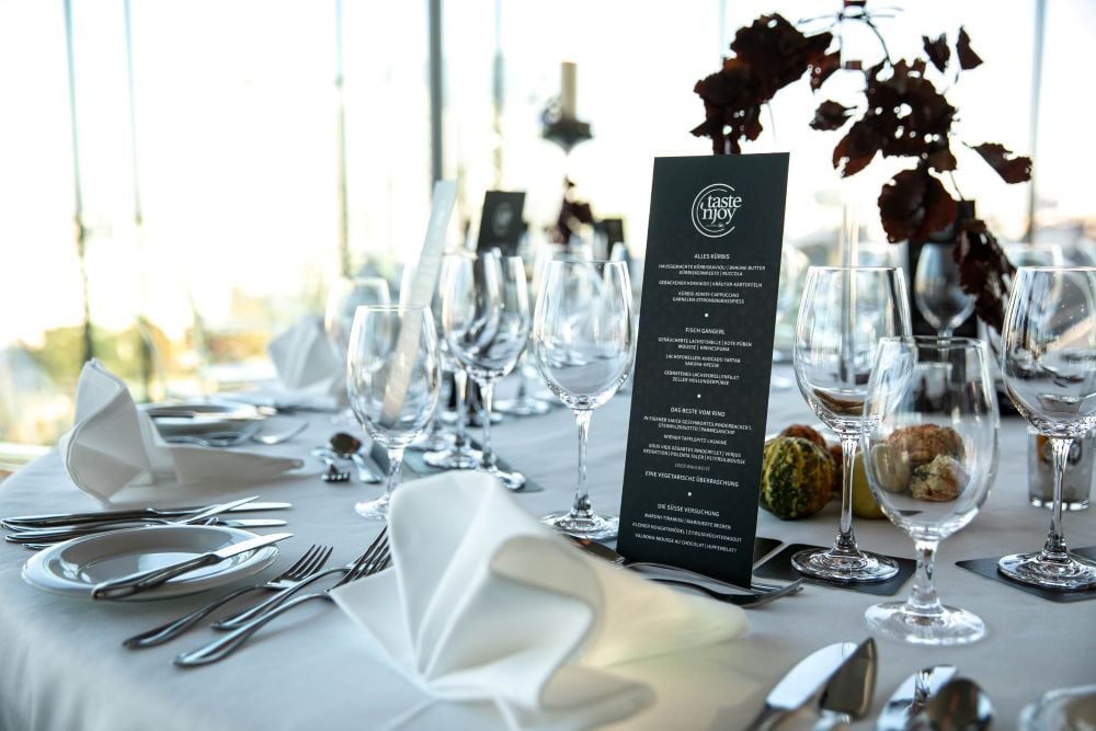 Menükarte, Gläser und festliche Tischdekoration bei einem exklusiven Event von taste'njoy Premium