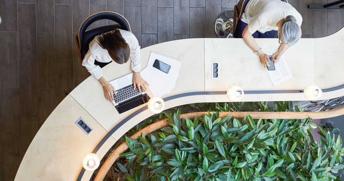 Blick von oben auf einen modernen Arbeitsbereich mit Laptop und Unterlagen für digitales Lernen.