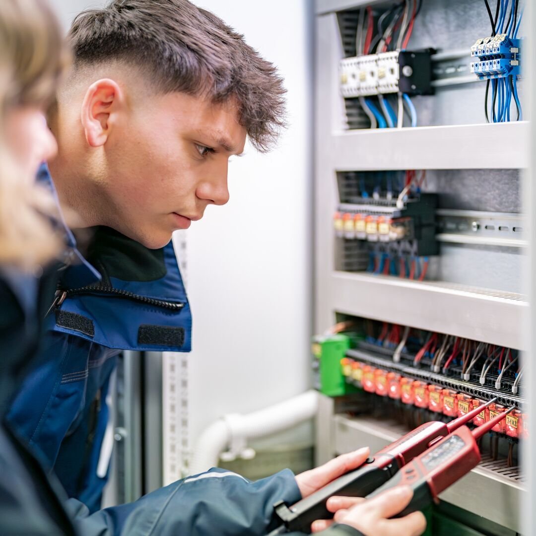 Servicetechniker führt Messungen an einem Schaltschrank durch und überprüft die Elektroinstallation.