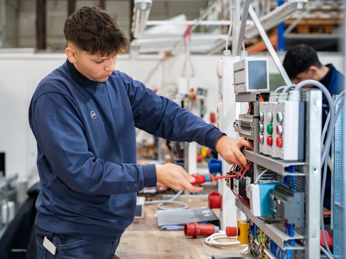 Mitarbeitender arbeitet an einer technischen Anlage in einer Werkstattumgebung.